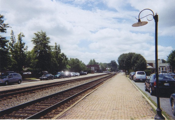 Picture of two train tracks with brick sidewalk and street on each side