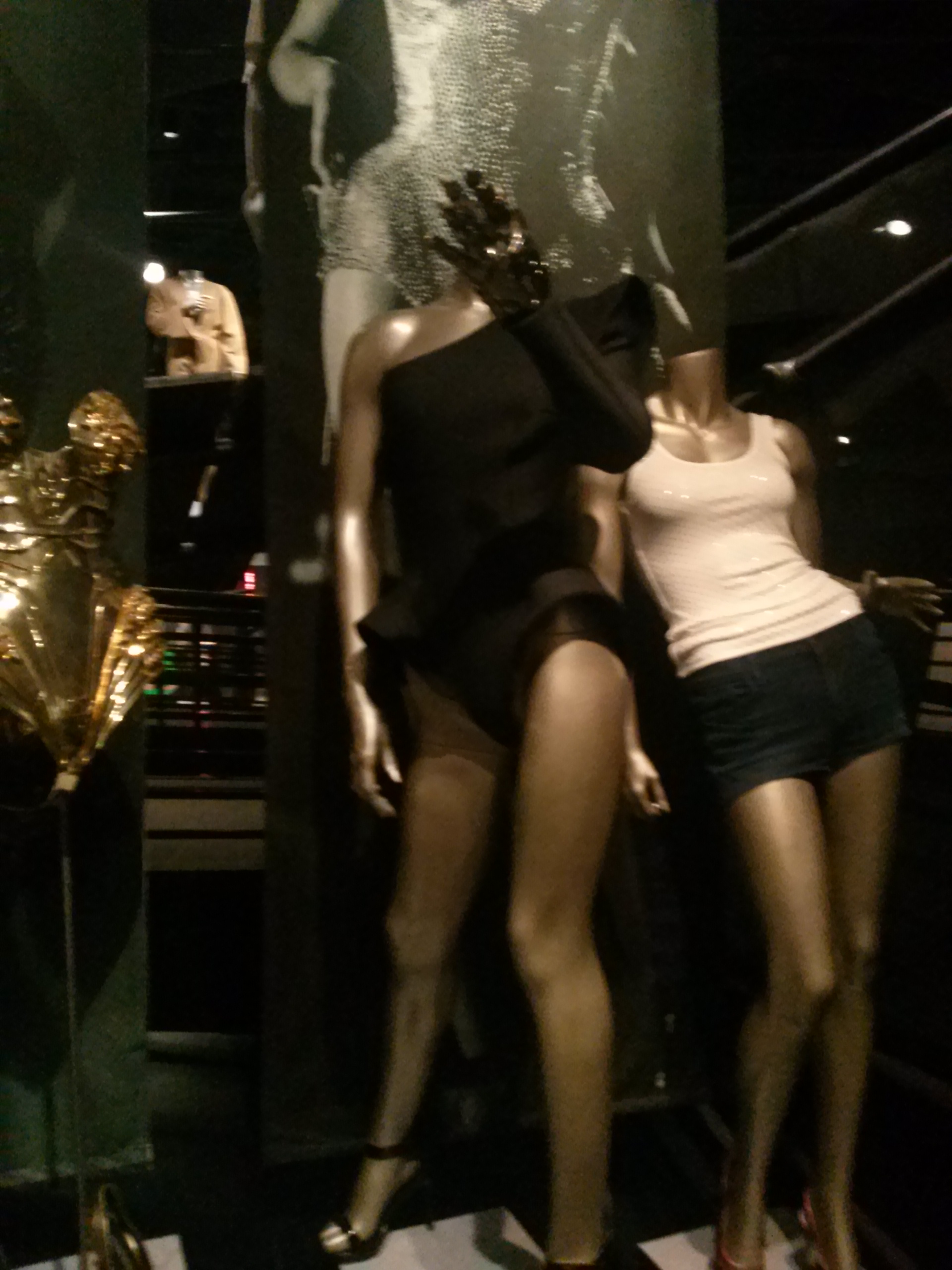Photograph: Beyoncé's outfits, with a gold bathing suit-like outfit, a black bathing suit-like outfit on a mannequin with left hand raised in black glove with a ring on it, and another mannequin with short sleaved pink top and very short black mini-skirt.