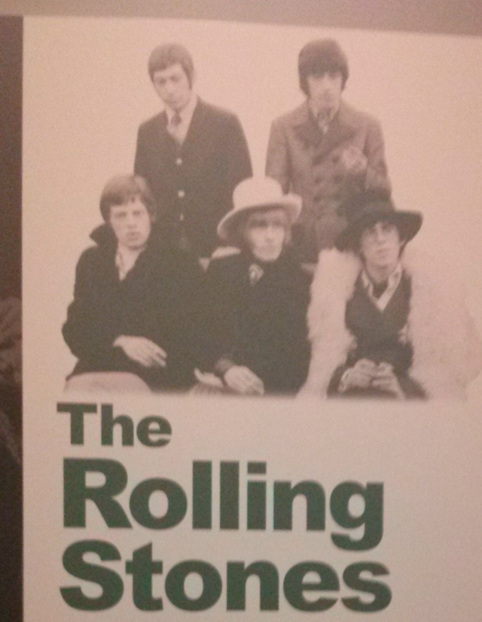 Photograph: Top portion of The Rolling Stones introduction panel with picture of Mick Jagger, Keith Richards, Brian Jones sitting and Bill Wyman and Charlie Watts standing behind them.